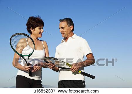 Stock Photo - USA, California, San Francisco, Mature couple with tennis rackets. Fotosearch