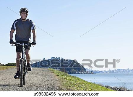 Stock Photograph - USA, California, Tiburon, Cyclist at lakeside. Fotosearch