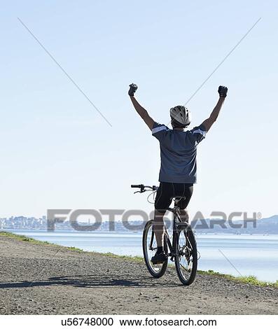 Stock Image - USA, California, Tiburon, Cyclist on lakeside. Fotosearch