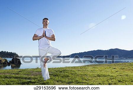 Stock Photograph - USA, California, Tiburon, Man practicing yoga on lakeside. Fotosearch