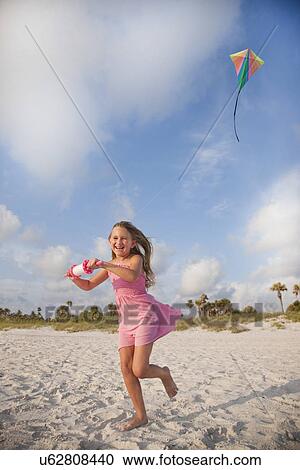 Stock Image - USA Florida, Girl (8-9) flying kite on St. Pete Beach. Fotosearch
