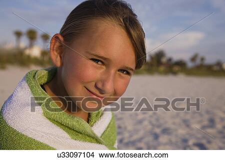 Picture - USA, Florida, St. Pete Beach, girl (8-9) wrapped in towel sitting on beach. Fotosearch