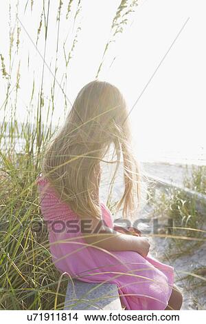 Picture - USA, Florida, St. Pete Beach, Girl (8-9) sitting on wooden rail on beach. Fotosearch