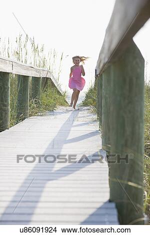 Picture - USA, Florida, St. Pete Beach, Girl (8-9) running on boardwalk. Fotosearch