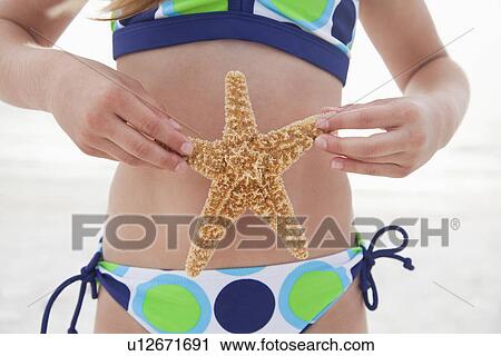 USA, Florida, St. Pete Beach, Girl (8-9) holding starfish in front of stomach on beach, mid section View Large Photo Image Stock Image - USA, Florida, St. Pete Beach, Girl (8-9) holding starfish in front of stomach on beach, mid section. Fotosearch