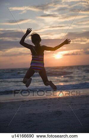 Stock Image - USA, Florida, St. Pete Beach, girl (8-9) jumping on beach. Fotosearch