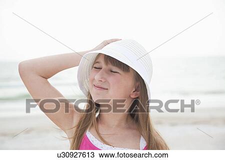 Stock Image - USA, Florida, St. Pete Beach, Girl (8-9) in sun hat on beach. Fotosearch