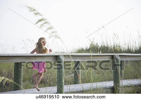 Stock Image - USA, Florida, St. Pete Beach, Girl (8-9) running on boardwalk. Fotosearch