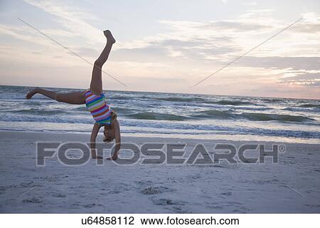 Stock Image - USA, Florida, St. Pete Beach, girl (8-9) cartwheeling on beach. Fotosearch