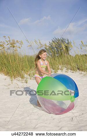 Stock Photo - USA, Florida, St. Pete Beach, Girl (8-9) playing with large colorful ball on beach. Fotosearch