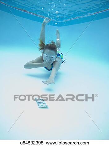 Stock Photo - USA, Florida, St. Pete Beach, Girl (8-9) swimming in pool and reaching for one dollar banknote. Fotosearch