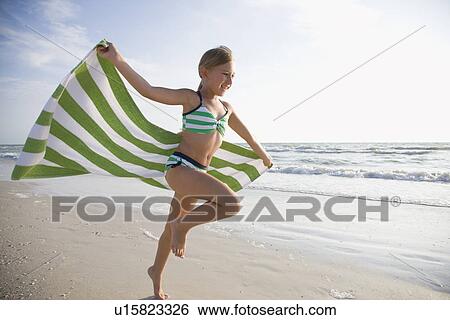 Stock Photograph - USA, Florida, St. Pete Beach, girl (8-9) running with towel on beach. Fotosearch