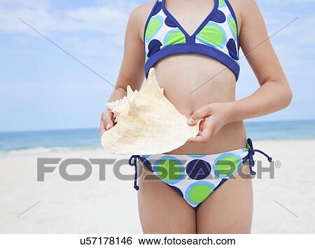 USA, Florida, St. Pete Beach, Girl (8-9) holding conch shell on beach, mid section View Large Photo Image Stock Photograph - USA, Florida, St. Pete Beach, Girl (8-9) holding conch shell on beach, mid section. Fotosearch