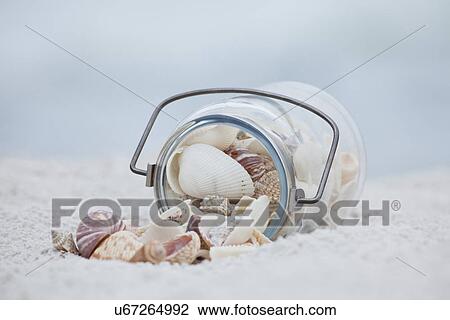 Stock Image - USA, Florida, St. Pete Beach, Jar of seashells on beach. Fotosearch