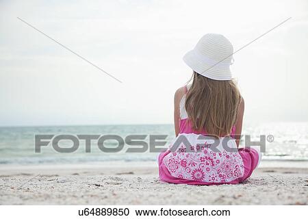 Stock Image - USA, Florida, St. Pete Beach, Rear view of girl (8-9) sitting on beach. Fotosearch