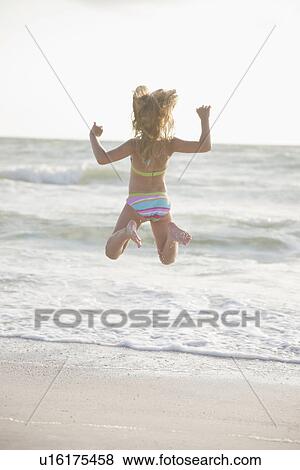 USA, Florida, St. Pete Beach, Rear view of girl (8-9) in bikini jumping on beach View Large Photo Image Stock Photo - USA, Florida, St. Pete Beach, Rear view of girl (8-9) in bikini jumping on beach. Fotosearch