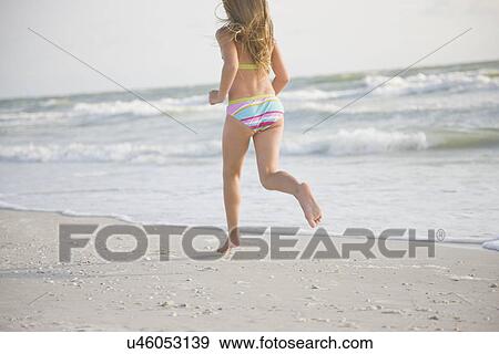 Stock Photo - USA, Florida, St. Pete Beach, Rear view of girl (8-9) in bikini running on beach. Fotosearch