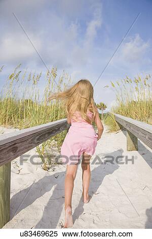 Stock Photography - USA, Florida, St. Pete Beach, Rear view of girl (8-9) running on beach. Fotosearch