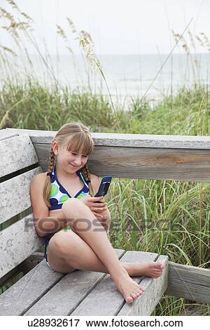 USA, Florida, St. Pete Beach, Smiling girl (8-9) texting on cell phone at beach View Large Photo Image Stock Photo - USA, Florida, St. Pete Beach, Smiling girl (8-9) texting on cell phone at beach. Fotosearch