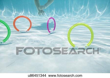 Picture - USA Florida, St. Pete Beach, Underwater shot of colorful circles on swimming pool floor, girl's (8-9) hands in background. Fotosearch
