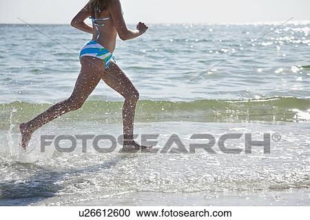 Stock Image - USA, Florida, St. Petersburg, girl (12-13) running along beach. Fotosearch