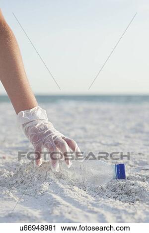 USA, Florida, St. Petersburg, Girl (10-11) cleaning beach, close-up of gloved hand reaching for plastic bottle View Large Photo Image Stock Image - USA, Florida, St. Petersburg, Girl (10-11) cleaning beach, close-up of gloved hand reaching for plastic bottle. Fotosearch