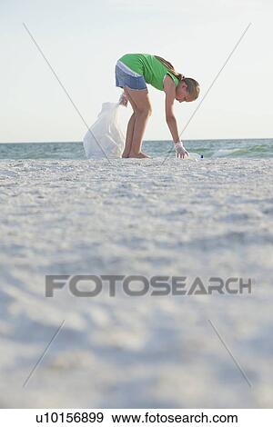 Stock Photo - USA, Florida, St. Petersburg, Girl (10-11) cleaning beach. Fotosearch