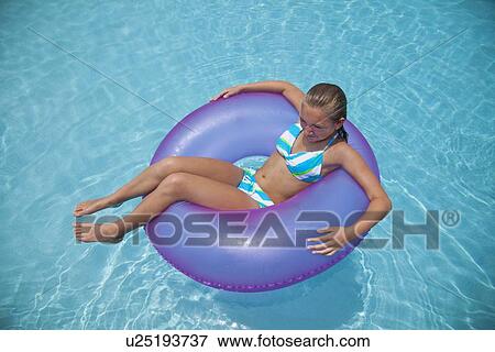 Stock Photo - USA, Florida, St. Petersburg, girl (12-13) floating on water in inflatable tube. Fotosearch
