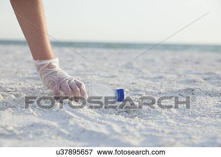 Stock Photo - USA, Florida, St. Petersburg, Girl (10-11) cleaning beach, close-up of gloved hand reaching for plastic bottle. Fotosearch