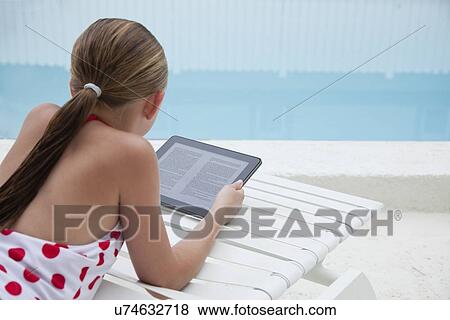 Stock Photo - USA, Florida, St. Petersburg, Girl (10-11) using digital tablet on poolside. Fotosearch
