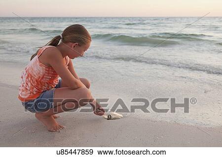 USA, Florida, St. Petersburg, Girl (10-11) reaching for bottle with money on beach View Large Photo Image Stock Photo - USA, Florida, St. Petersburg, Girl (10-11) reaching for bottle with money on beach. Fotosearch