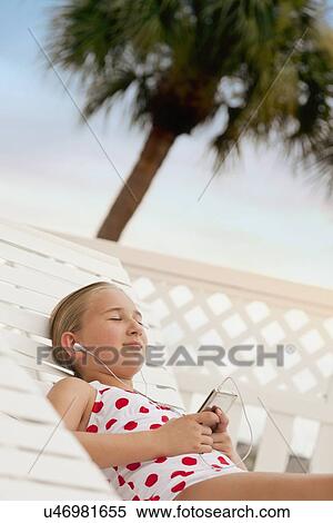 Stock Photography - USA, Florida, St. Petersburg, Girl (10-11) with mp3 player relaxing on beach. Fotosearch