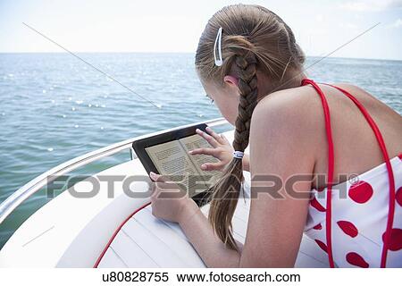 Stock Photography - USA, Florida, St. Petersburg, Girl (10-11) using digital tablet on yacht. Fotosearch