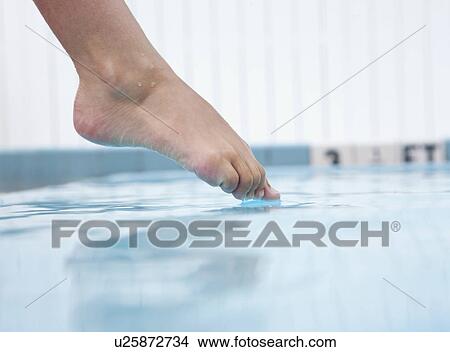 Picture - USA, Florida, St. Petersburg, Girl's (10-11) foot touching water in swimming pool. Fotosearch
