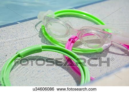 Stock Photograph - USA, Florida, St. Petersburg, goggles and rings on poolside. Fotosearch