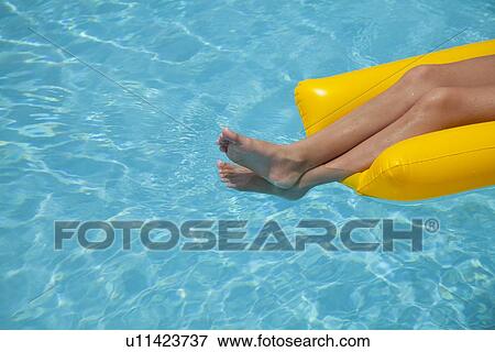 Stock Photo - USA, Florida, St. Petersburg, low section of girl (12-13) floating on water in pool raft. Fotosearch