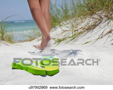 Stock Photo - USA, Florida, St. Petersburg, Pair of flip flops on sandy beach and girl (12-13) in background. Fotosearch