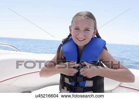 Picture - USA, Florida, St. Petersburg, Portrait of smiling girl (10-11) fastening life jacket in speedboat. Fotosearch