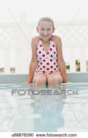Stock Image - USA, Florida, St. Petersburg, Portrait of smiling girl (10-11) sitting in swimming pool. Fotosearch