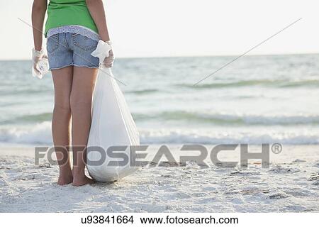 USA, Florida, St. Petersburg, Rear view of girl (10-11) standing on beach with garbage bag, facing ocean View Large Photo Image Picture - USA, Florida, St. Petersburg, Rear view of girl (10-11) standing on beach with garbage bag, facing ocean. Fotosearch