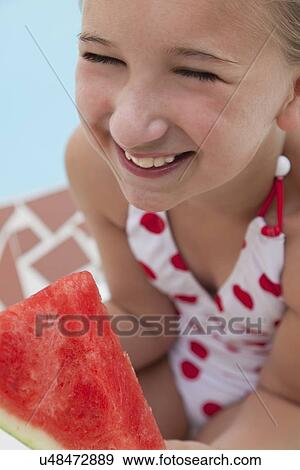 Stock Photo - USA, Florida, St. Petersburg, Smiling girl (10-11) holding slice of watermelon. Fotosearch