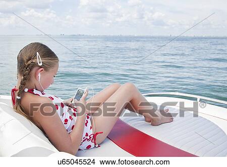 Picture - USA, Florida, St. Petersburg, Smilling girl (10-11) listening music on yacht. Fotosearch