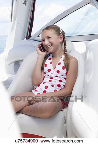 Stock Image - USA, Florida, St. Petersburg, Smilling girl (10-11) talking on mobile phone on yacht. Fotosearch
