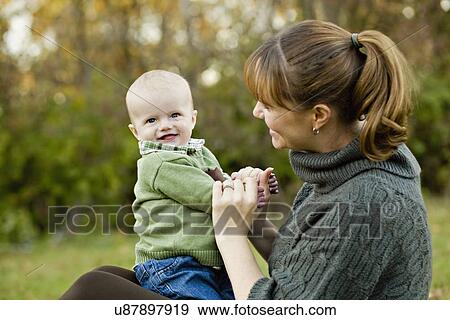USA, Illinois, Brimfield, Mother with son (6-11 months) sitting in Autumn park View Large Photo Image Stock Photo - USA, Illinois, Brimfield, Mother with son (6-11 months) sitting in Autumn park. Fotosearch