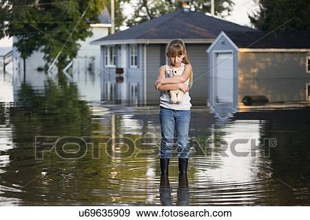 Stock Photo - USA, Illinois, Chillicothe, Girl (8-9) carrying teddy bear and standing in water. Fotosearch