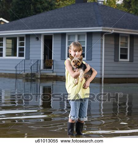 Stock Photography - USA, Illinois, Chillicothe, Girl (8-9) carrying Yorkshire terrier and standing in water. Fotosearch