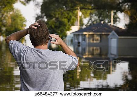 Stock Photo - USA, Illinois, Chillicothe, Mid adult man talking on phone, rear view. Fotosearch