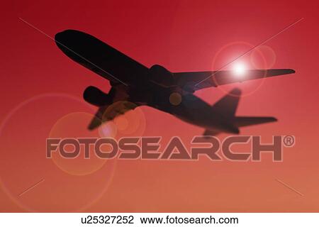 Stock Image - USA, Illinois, Metamora, Airplane flying at sunset. Fotosearch