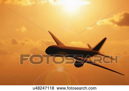 Stock Photo - USA, Illinois, Metamora, Airplane flying at sunset. Fotosearch