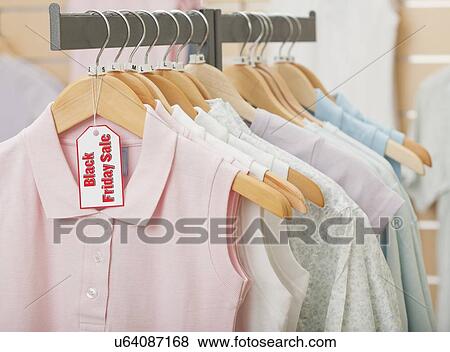 Stock Photo - USA, Illinois, Metamora, Black Friday sale tag on clothing hanging on rail in shop. Fotosearch